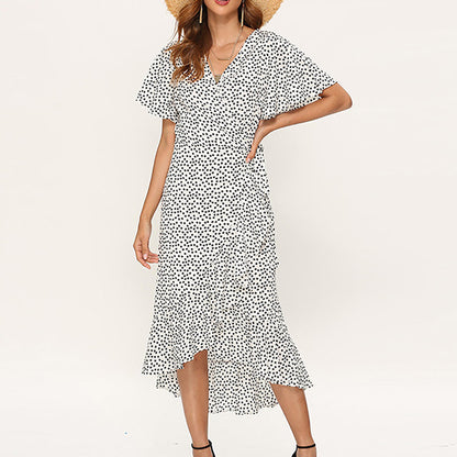 Frau in weißem gepunktetem Sommerkleid mit V-Ausschnitt und Strohhut, modisch, elegant.