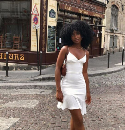 Frau in weißem Sommerkleid auf Kopfsteinpflasterstraße vor Café in Paris.