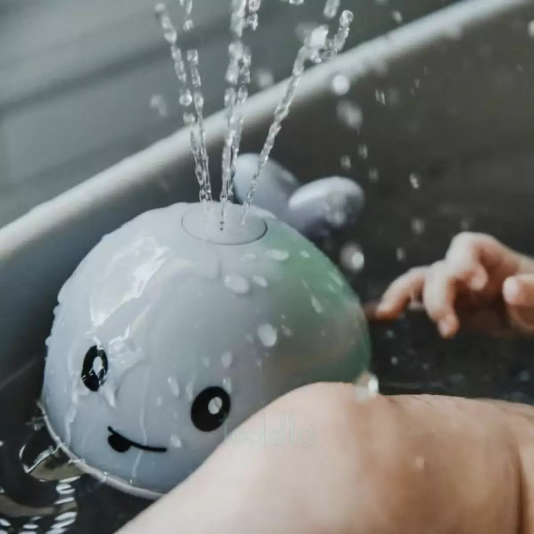 Grauer Wal-Badespielzeug mit Wasserfontäne, schwimmend in der Badewanne, Kinderbadespielzeug.