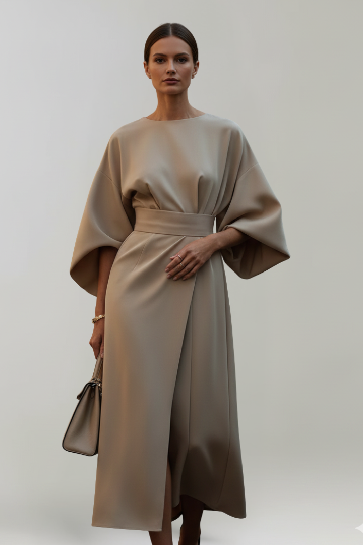 Modell i beige klänning med vida ärmar och bälte, framifrån med beige handväska 6