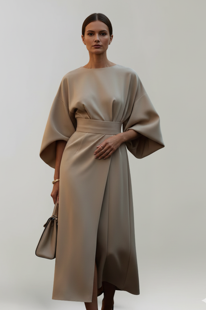 Modell i beige klänning med vida ärmar och bälte, framifrån med beige handväska 6