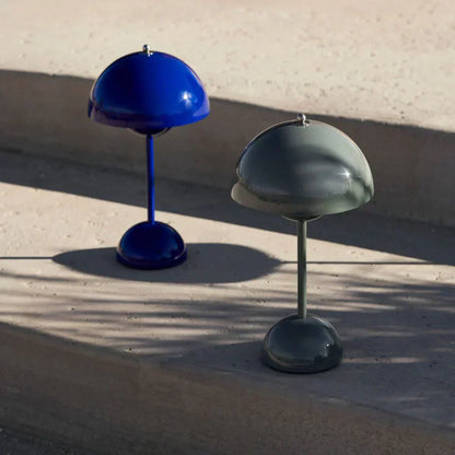 Dunkelblaue und graue Tischlampen aus Metall auf Betonstufen, modernes Design.