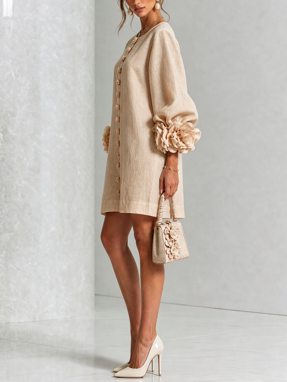 Beige miniklänning från sidan på modell, puffärmen med stor blommanschett syns tydligt, hon håller en liten beige handväska. 24