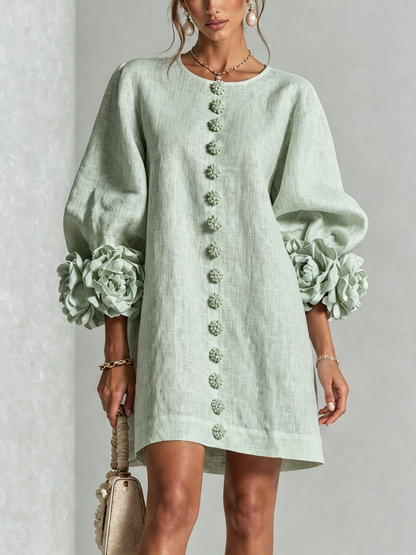 Ljusgrön miniklänning framifrån på modell i studio, med rad av blommiga knappar och stora blommanschetter på puffärmarna. 31