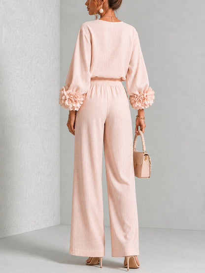 Modell i rosa set sedd bakifrån, med blommor på ärmarna och resårmidja på byxorna 9