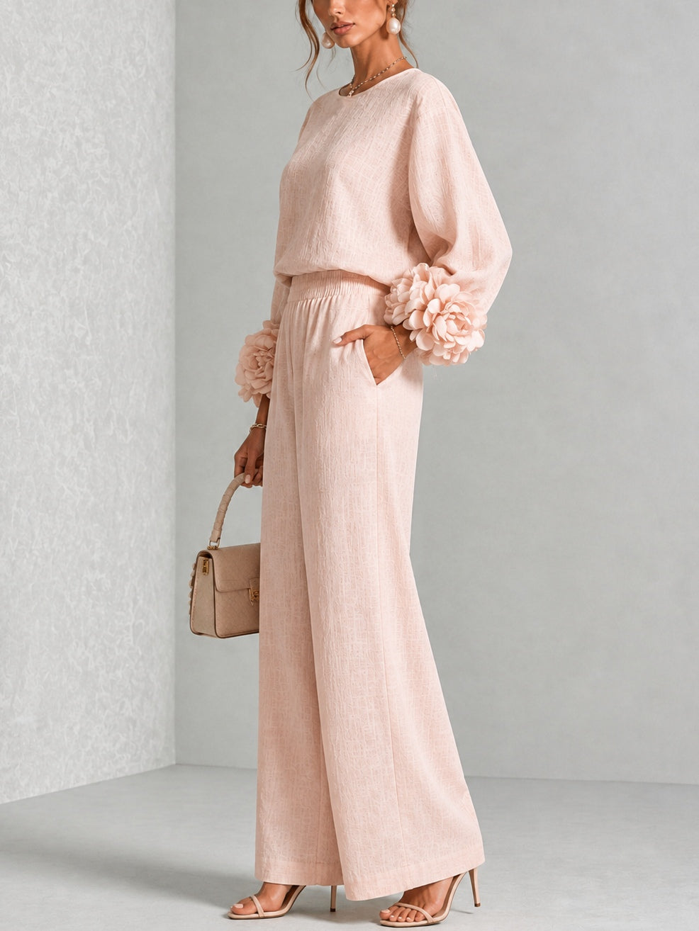 Modell i rosa set i halvprofil, med blomprydd ärm, hand i fickan och vida byxor 10