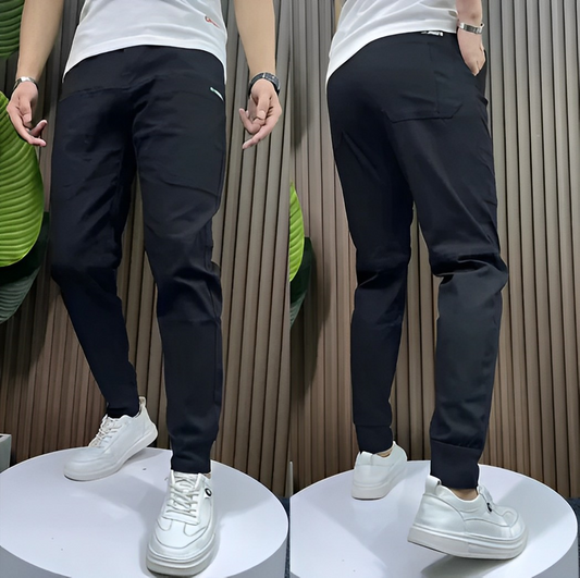 Schwarze Herren-Jogginghose, elastisch, bequem, sportlich, mit weißen Sneakers.