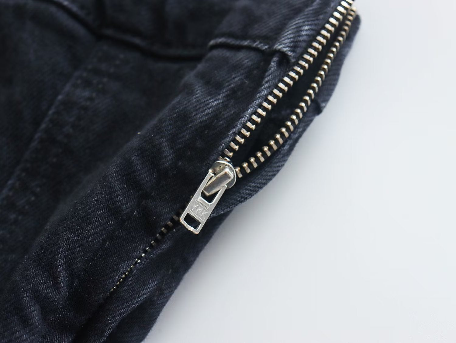 Schwarze Jeans mit silbernem Reißverschluss, Denim-Stoff, modisch, Detailaufnahme.