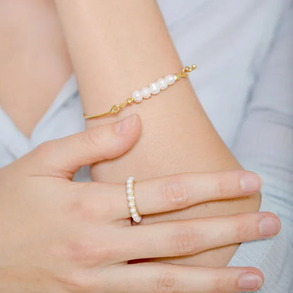 Goldenes Armband mit weißen Perlen, eleganter Schmuck, Damenmode, Hand, Nahaufnahme.