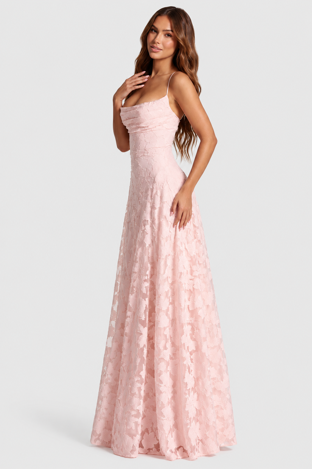 Rosa klänning i blommig spets, sedd från sidan på en modell med draperad halsringning och smala axelband. 1