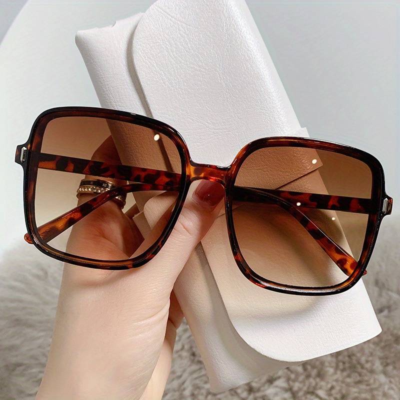 Braune übergroße Sonnenbrille mit Schildpattmuster, quadratische Gläser, in Hand gehalten.