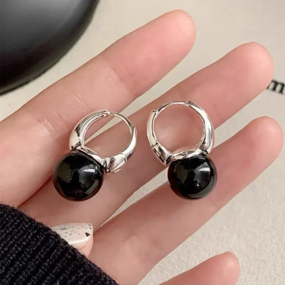 Silberne Ohrringe mit schwarzem Perlenanhänger, eleganter Schmuck, modisches Accessoire.