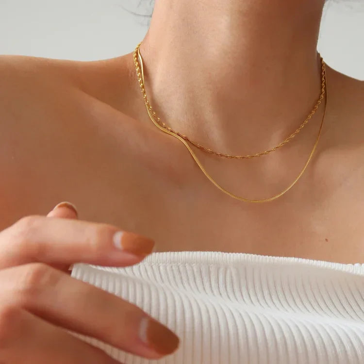 Frau trägt goldene Halskette, minimalistisch, elegant, Schmuck, Modeaccessoire, Nahaufnahme.