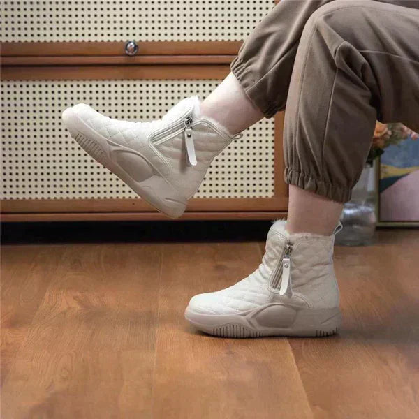 Weiße Winterstiefel mit Reißverschluss, warm gefüttert, auf Holzfußboden, Damenmode.