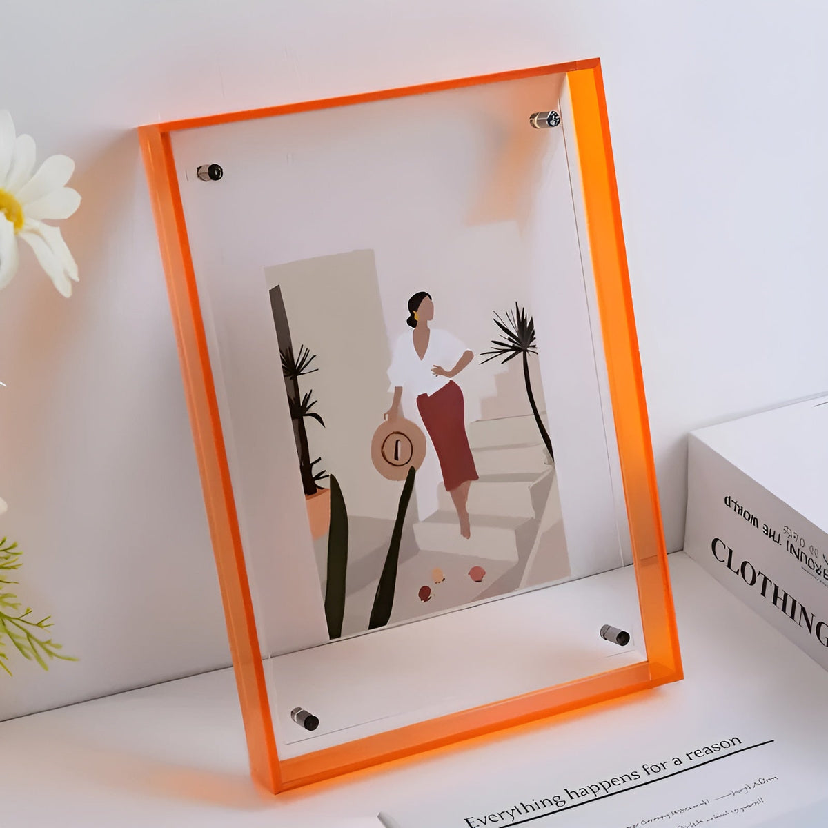 Orange akrylram med illustration av en kvinna med hatt vid en trappa, bredvid vita blommor och böcker. 10