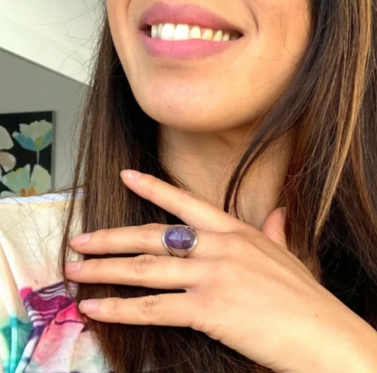 Frau trägt lila Amethyst-Ring, Silberfassung, lächelnd, Nahaufnahme, Schmuckmode.