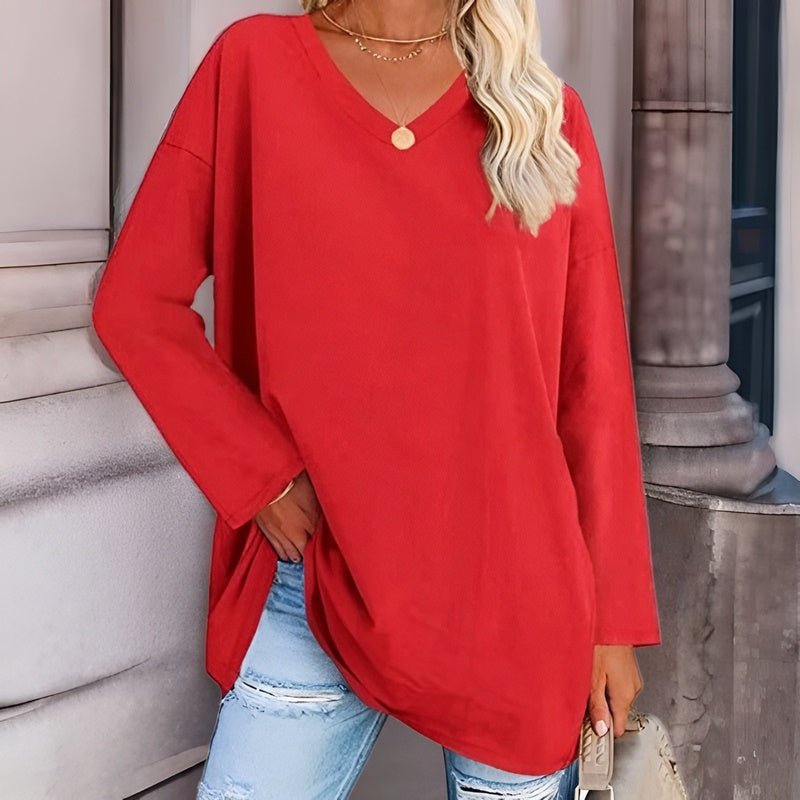 Frau in rotem Oversize-Pullover, V-Ausschnitt, zerrissene Jeans, modisch, urbaner Stil.