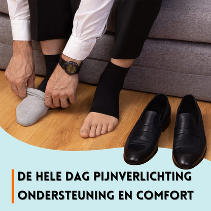 Mann zieht schwarze Kompressionssocken an, Lederschuhe, Holzboden, Schmerzlinderung.