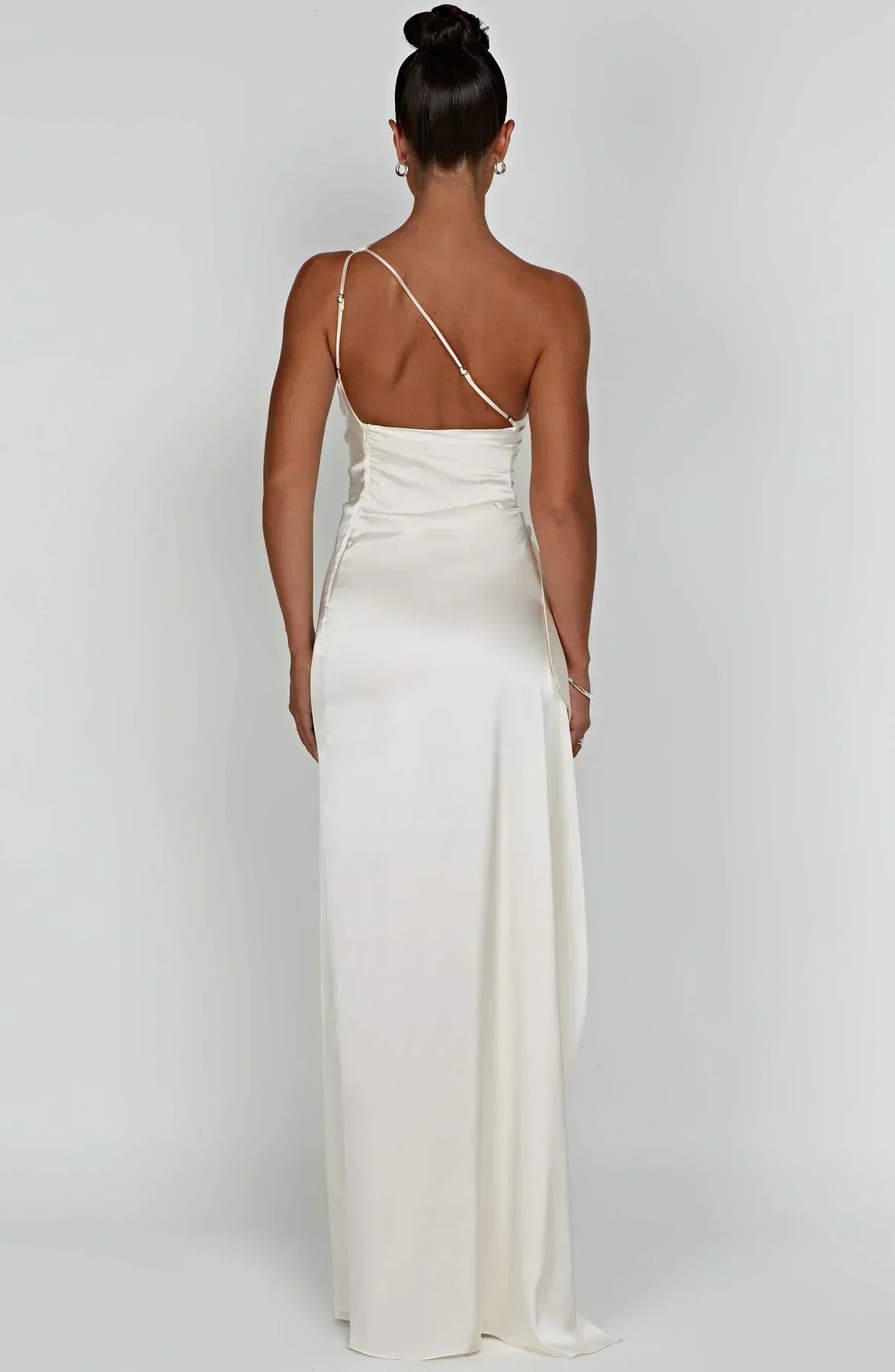 Frau in elfenbeinfarbenem Maxi-Kleid, rückenfrei, elegantes Abendkleid, Satin, schulterfrei.