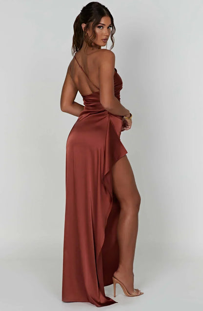 Frau in rostfarbenem Satin-Maxikleid mit Beinschlitz, elegantes Abendmode-Outfit.