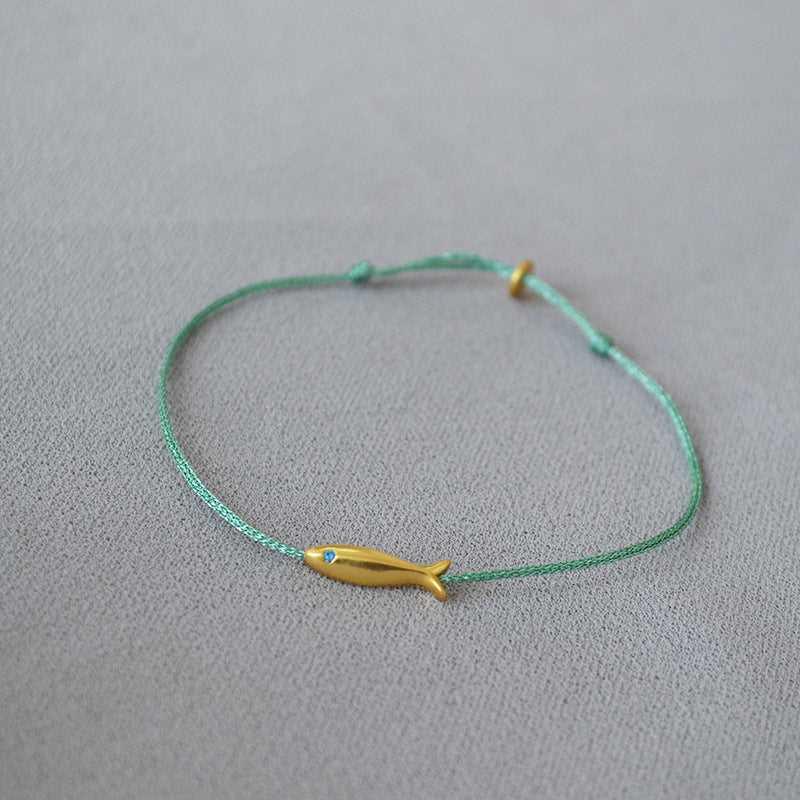 Grünes Armband mit gelbem Fischanhänger, minimalistisches Schmuckdesign, handgefertigt.