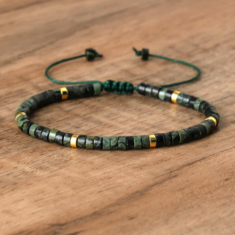 Grünes Perlenarmband mit goldenen Akzenten auf Holzoberfläche, verstellbar, handgefertigt.