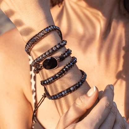 Frau trägt mehrlagiges Armband mit schwarzen Perlen und Kristallen im Sonnenlicht.