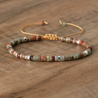 Armband aus Natursteinperlen, verstellbar, handgefertigt, mehrfarbig, auf Holztisch.