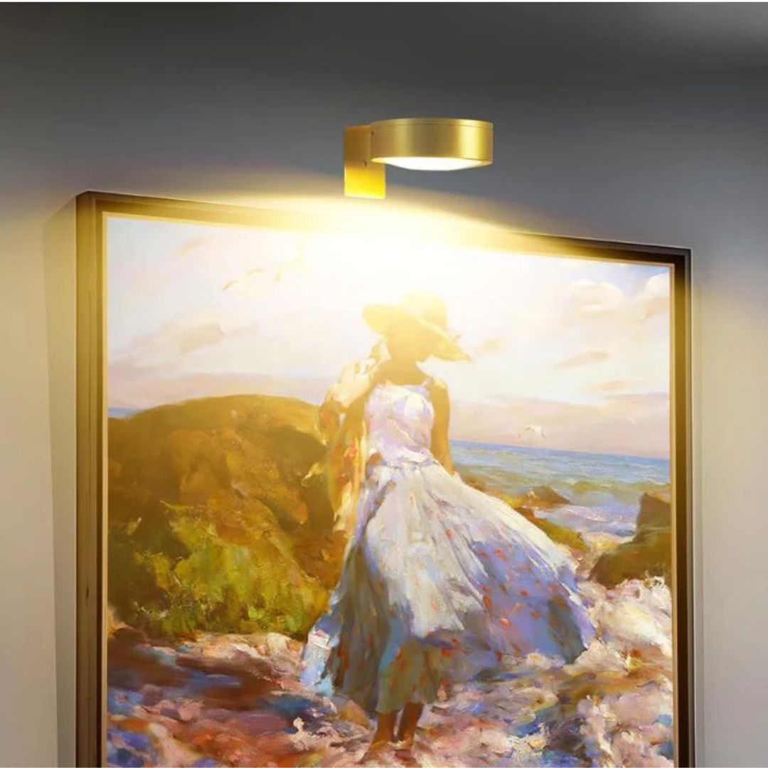Mässingsfärgad lampa lyser upp en inramad målning av en kvinna i hatt och klänning vid havet 8