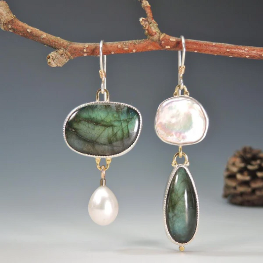 Unterschiedliche Ohrringe mit Labradorit, Perle und Silber, hängend an Ast, eleganter Schmuck.