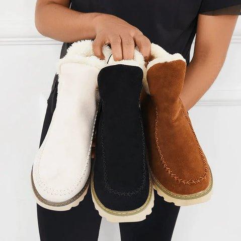 Tre par boots i vitt, svart och brunt hålls tillsammans av en modell, så att fleecefodret syns i skaften. 7