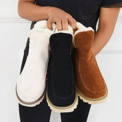 Tre par boots i vitt, svart och brunt hålls tillsammans av en modell, så att fleecefodret syns i skaften. 7
