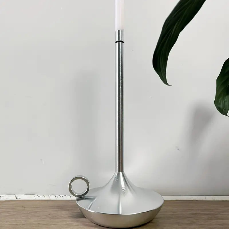 Silberner Kerzenhalter aus Metall mit modernem Design auf Holzoberfläche, minimalistisch.