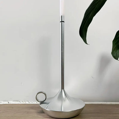 Silberner Kerzenhalter aus Metall mit modernem Design auf Holzoberfläche, minimalistisch.