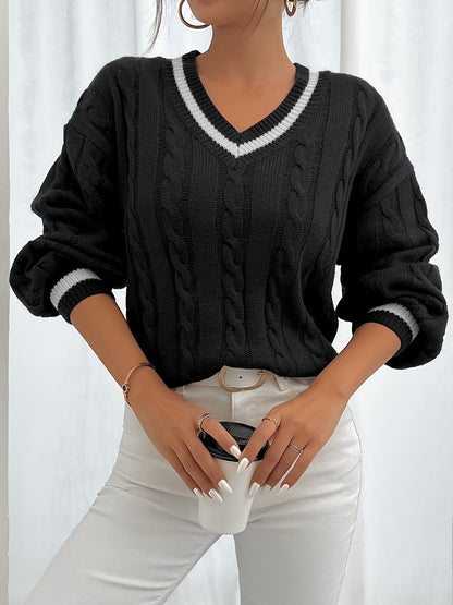 Frau in schwarzem Strickpullover mit V-Ausschnitt und weißen Details, hält Kaffeetasse.