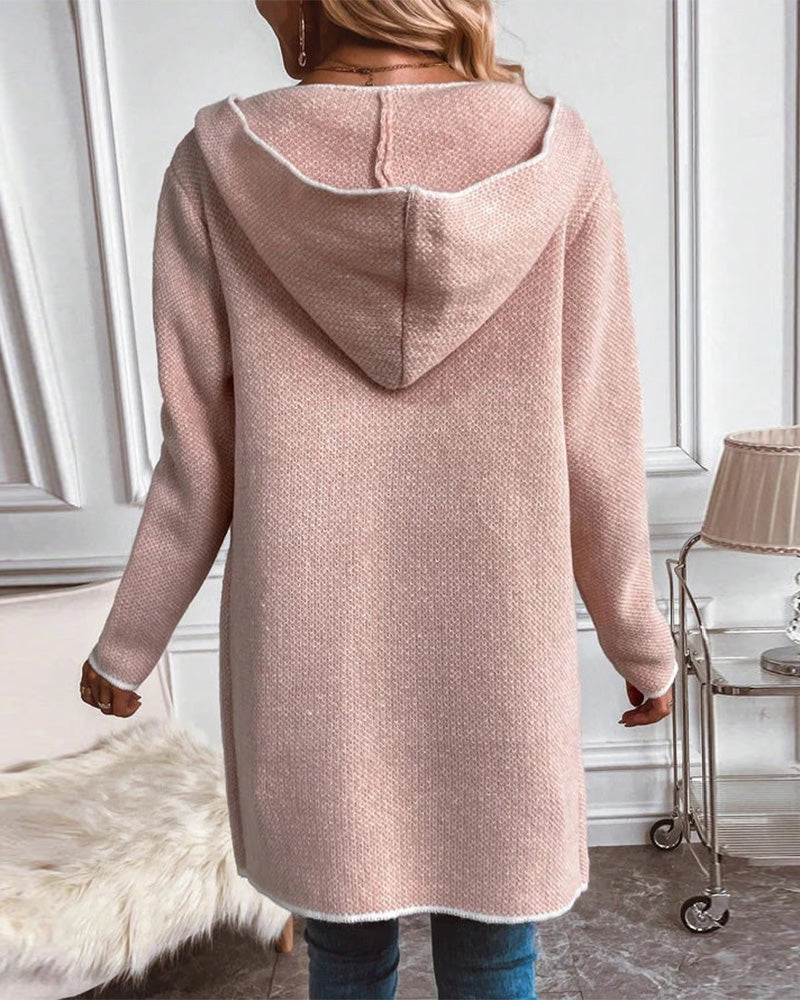 Frau in rosa Strickjacke mit Kapuze, Rückansicht, modisch, gemütlich, Wohnzimmer-Hintergrund.