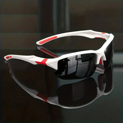 Weiße Sportsonnenbrille mit roten Akzenten und schwarzen Gläsern auf reflektierender Oberfläche.