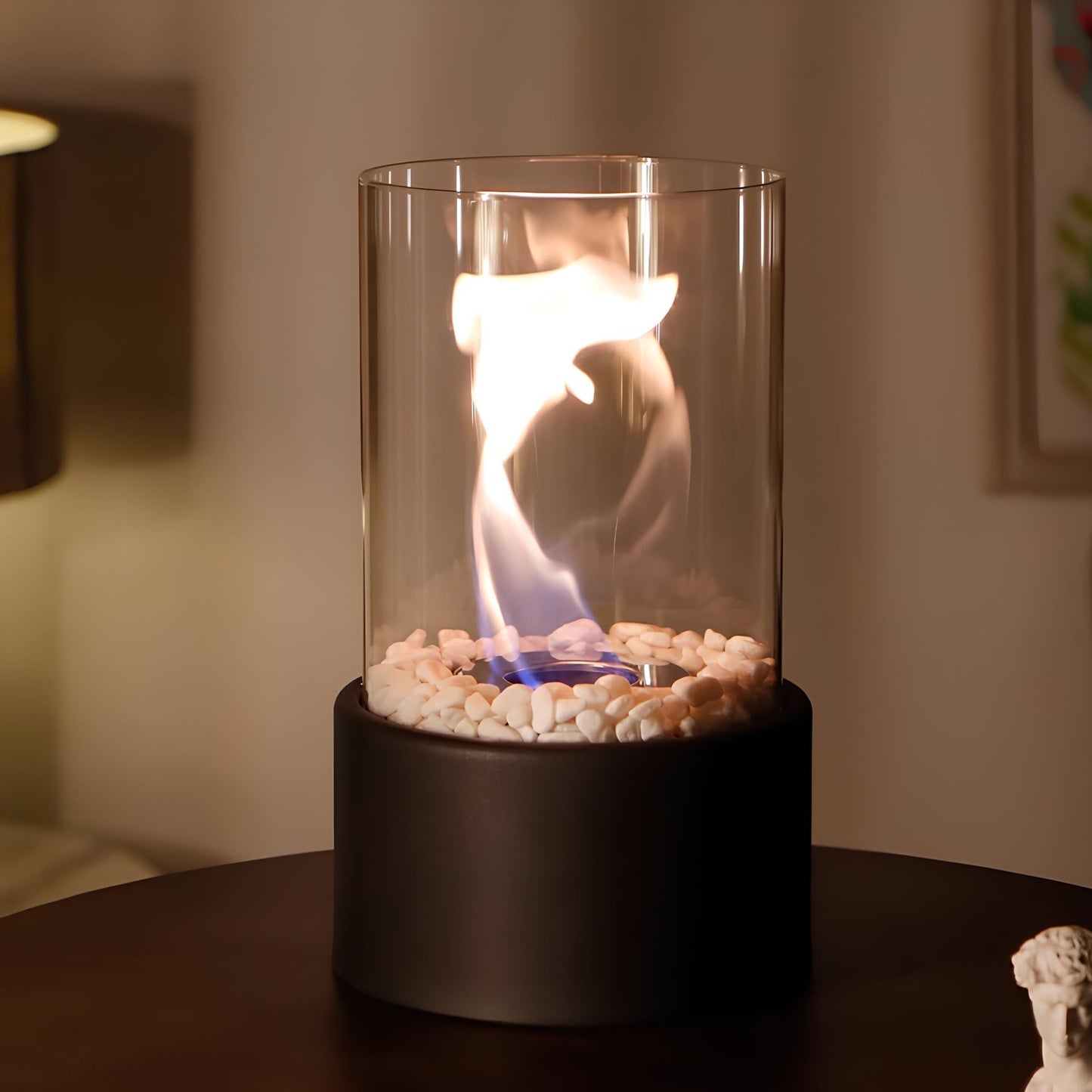 Tischkamin Glaszylinder mit Flamme, schwarze Basis, Dekosteine, modernes Design, Innenbereich.
