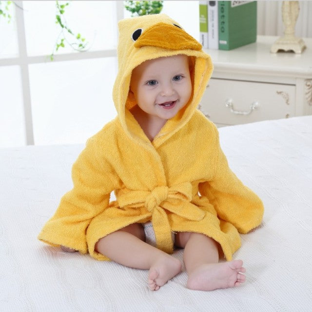 Kleinkind in gelbem Enten-Bademantel auf Bett, lächelnd, niedlich, Baby-Bademode.