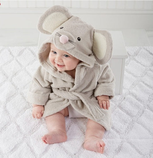 Baby in grauem Bademantel mit Mauskapuze auf weißer Decke sitzend.
