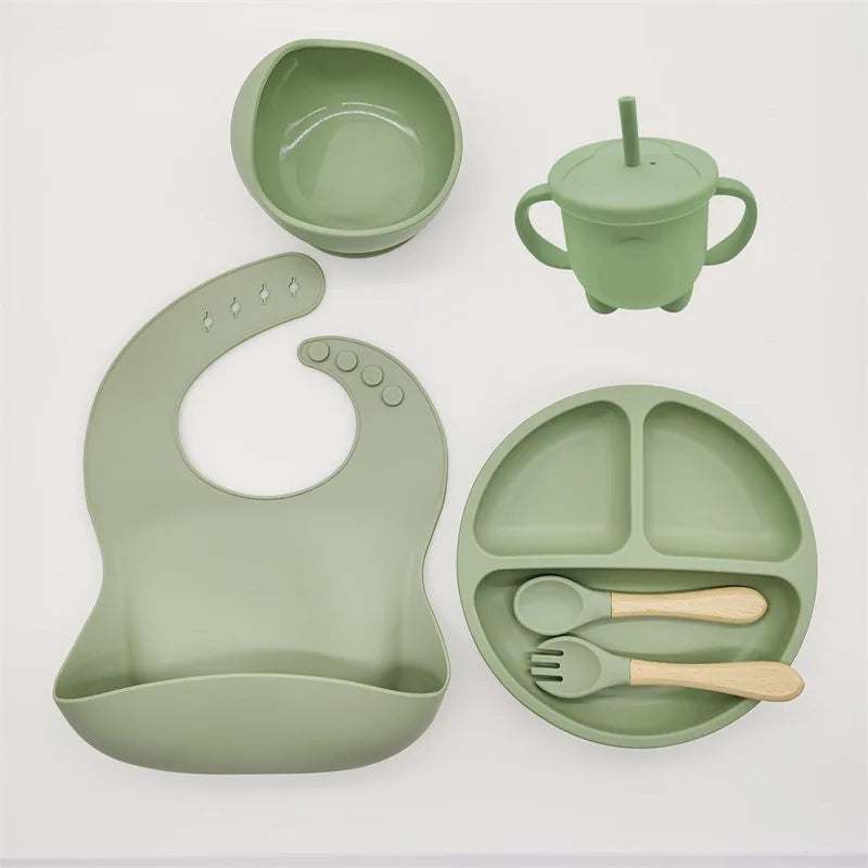 Grünes Silikon-Babygeschirr-Set mit Lätzchen, Teller, Becher, Schüssel und Besteck.