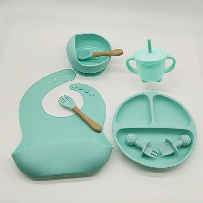 Baby-Essgeschirr-Set aus Silikon in Mintgrün, bestehend aus Lätzchen, Teller, Becher und Besteck.