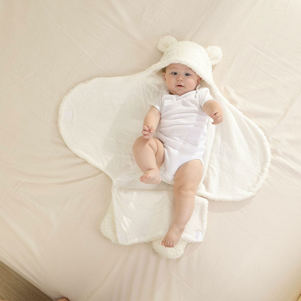 Baby in weißem Teddy-Fußsack auf Bett, weiches Material, kuschelig, Neugeborenen-Zubehör.