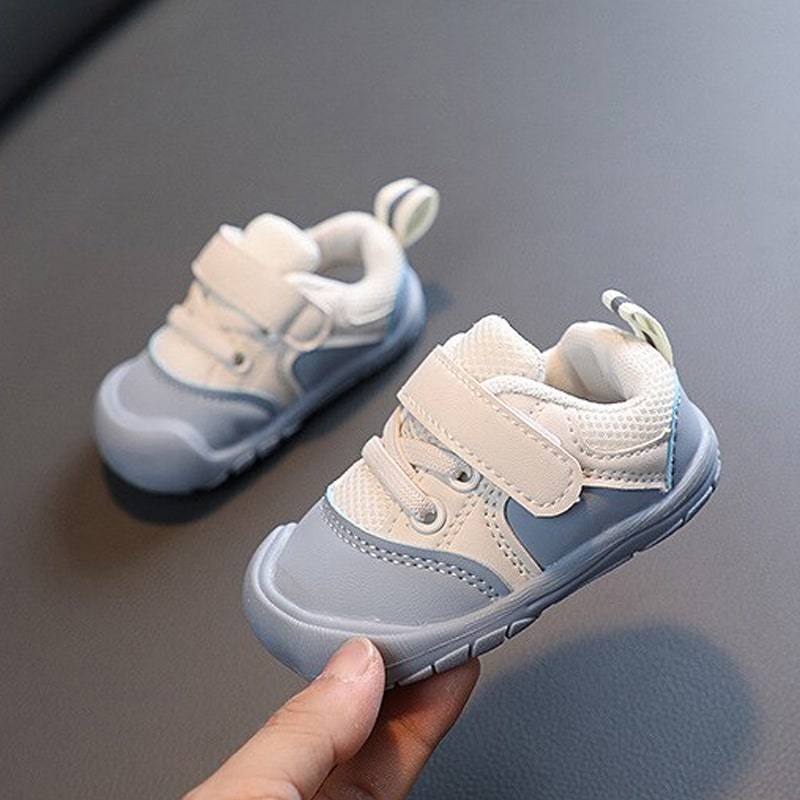 Graue und weiße Babyschuhe mit Klettverschluss, rutschfeste Sohle, ideal für Kleinkinder.