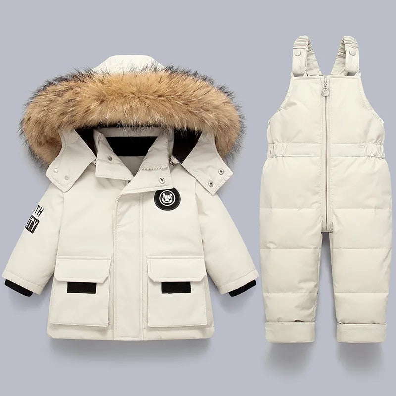 Baby-Winterset: Weiße Daunenjacke mit Fellkapuze und Latzhose für Kleinkinder.