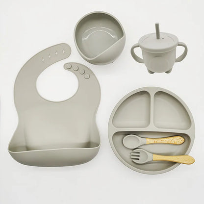 Graues Silikon-Babygeschirr-Set mit Lätzchen, Teller, Schüssel, Becher und Besteck.