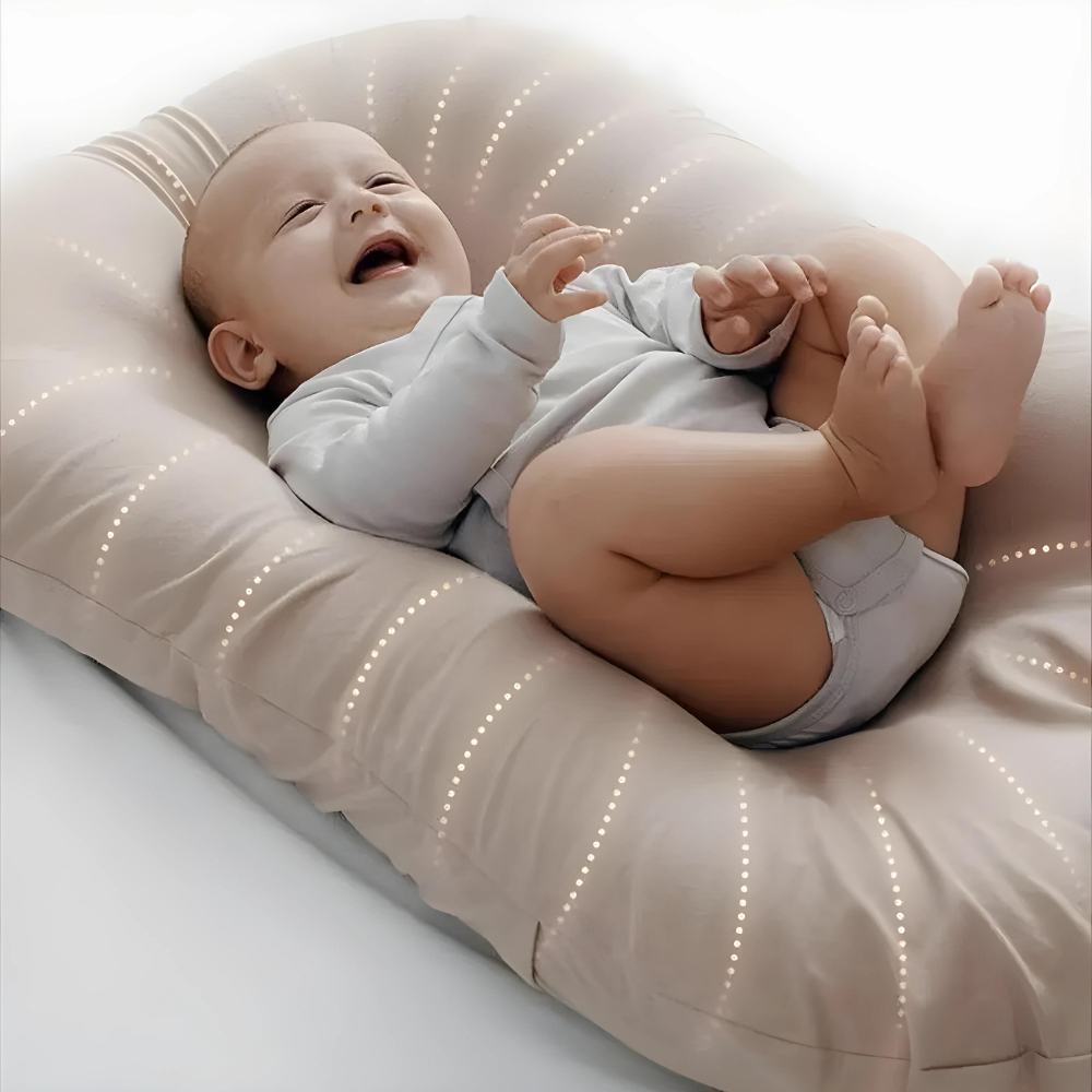 Lachendes Baby auf beigem Babynest, weich gepolstert, ideal für Neugeborene, gemütlich und sicher.