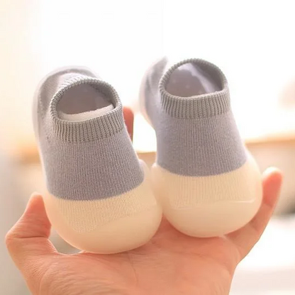 Graue Babyschuhe aus Baumwolle mit rutschfester Sohle, ideal für Kleinkinder.