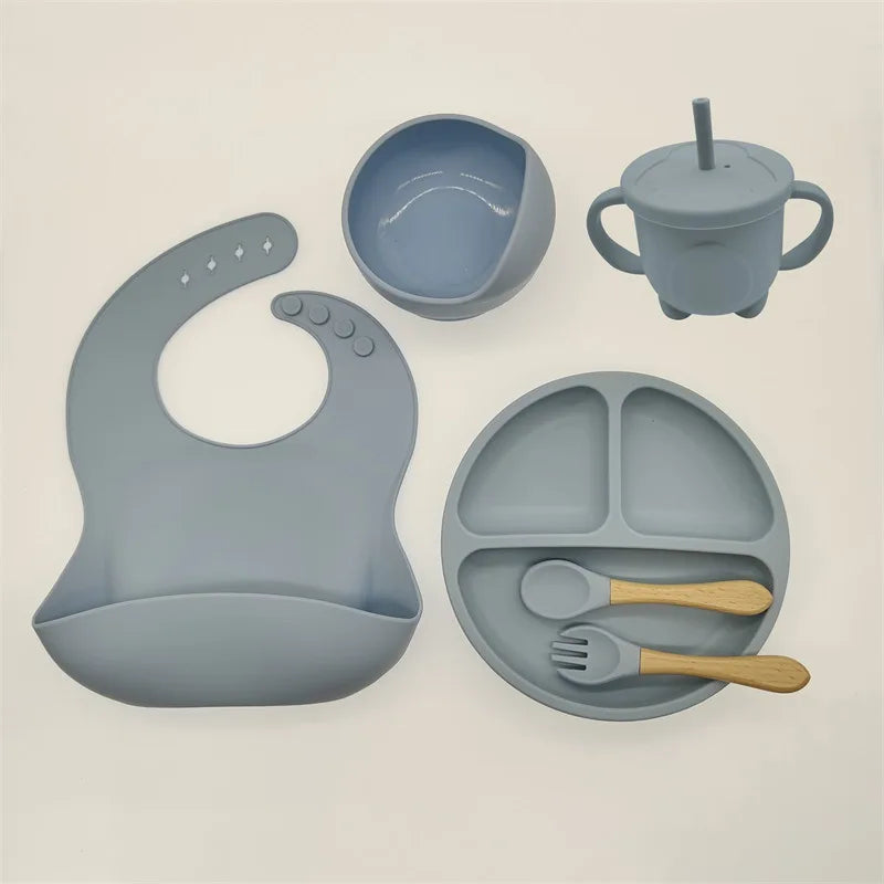 Graues Silikon-Babygeschirr-Set mit Lätzchen, Teller, Schüssel, Becher und Besteck.