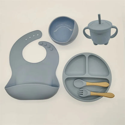 Graues Silikon-Babygeschirr-Set mit Lätzchen, Teller, Schüssel, Becher und Besteck.